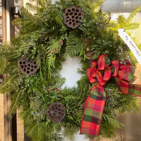 A beautiful wreath made with evergreen boughs, lotus pots and a big red bow